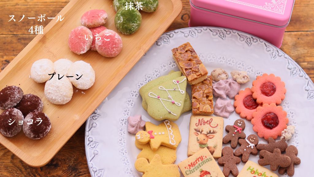 ピンク色のNoël Tin缶に詰められたクッキー。スノーボール4種(プレーン、ショコラ、いちご、抹茶)、トナカイやジンジャーマンのアイシングクッキー、ナッツ菓子、ジャムサンドクッキーが美しく並ぶ。