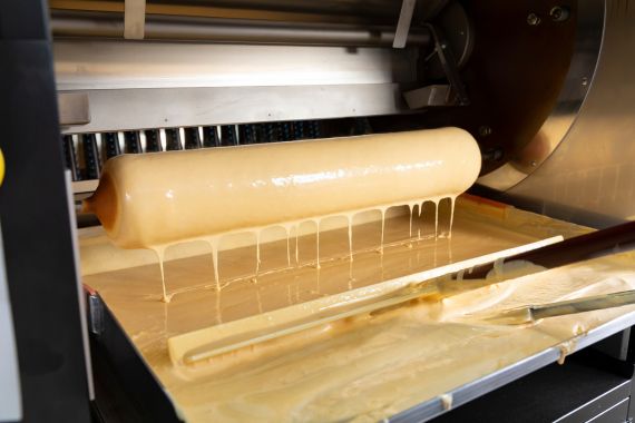 バウムクーヘンが回転式オーブンで焼かれている製造中の様子