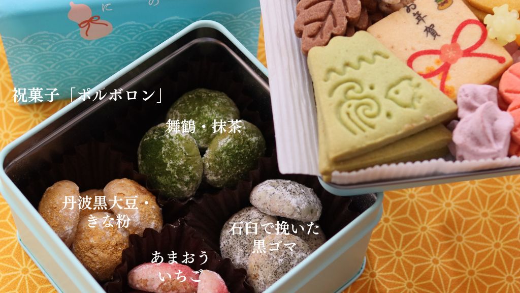 水色の和柄缶に詰められたポルボロン4種(抹茶、きな粉、黒ごま、いちご)と、お正月モチーフのプリントクッキーや干支菓子が見える。