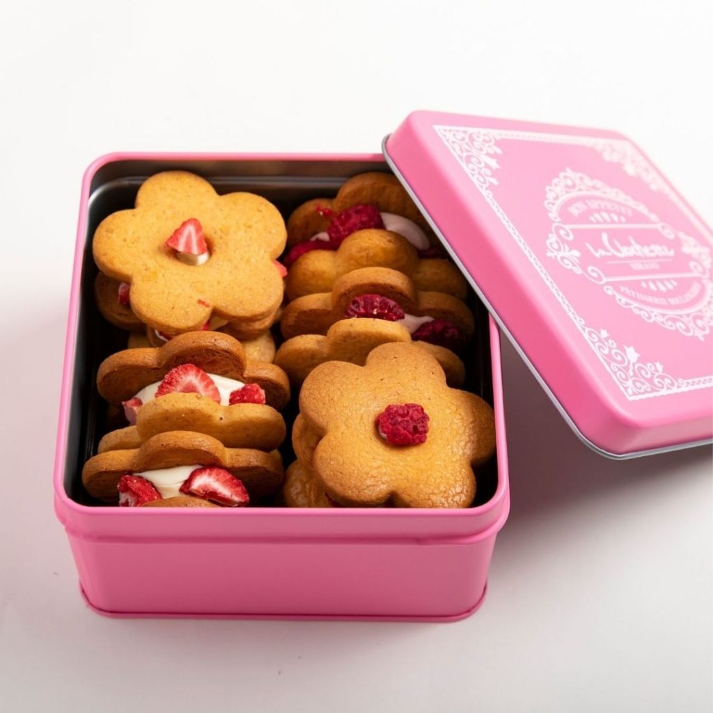 ピンク色の缶に詰められた花型バターサンドクッキー。バニラバタークリーム＆いちご、イチゴバタークリーム＆フランボワーズの2種類入り。